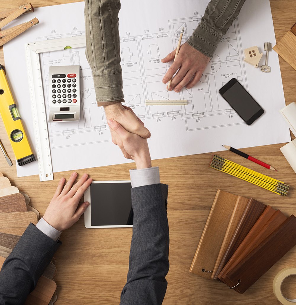 Contractor and homeowner shaking hands over plans